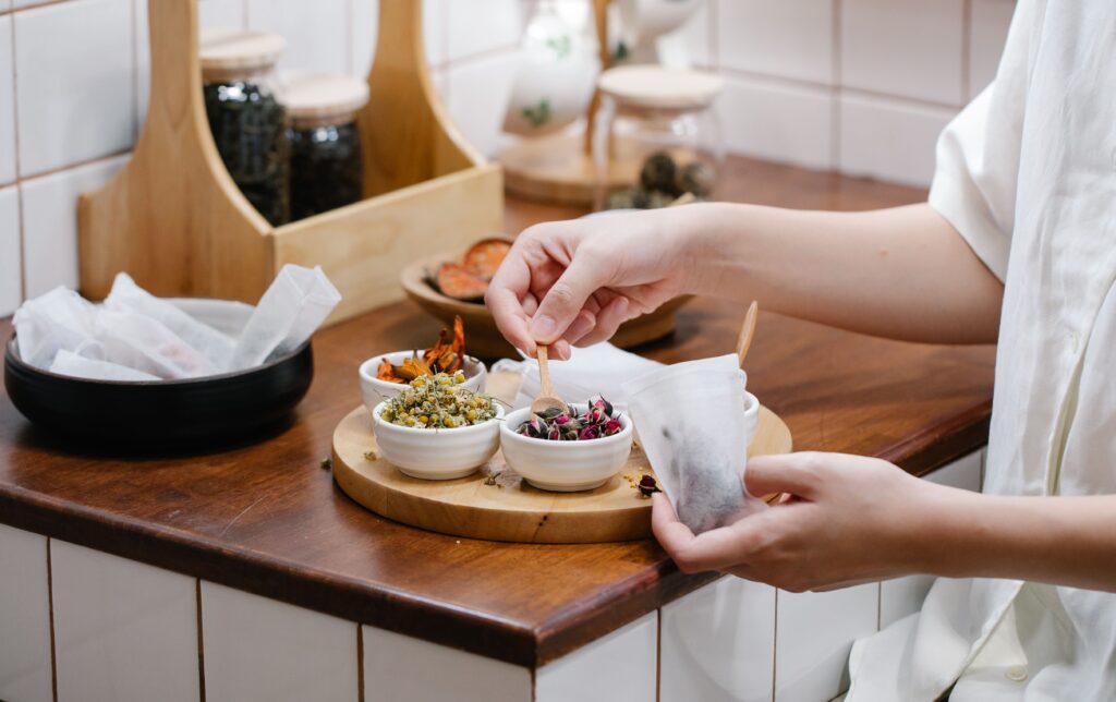 Close-up of hands preparing herbal tea with fresh ingredients in a cozy kitchen.